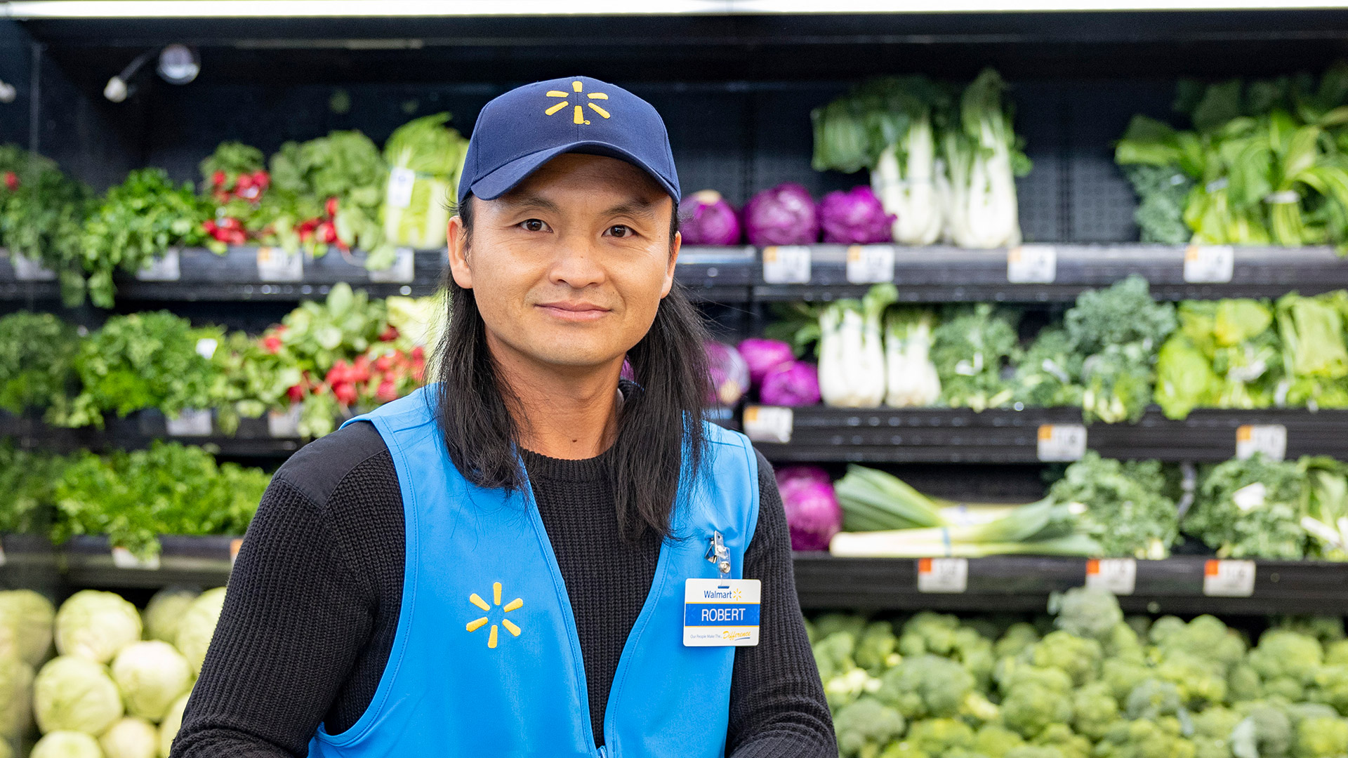 Associate Robert in front of produce wall